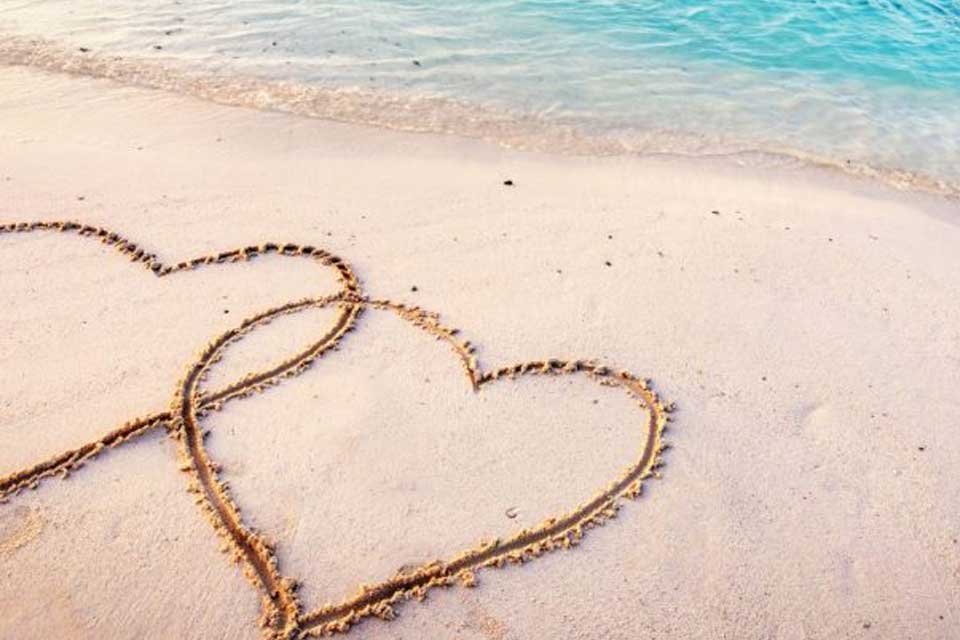 нарисувани сърца в пясъка на плажа